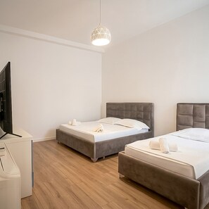 Ein Hotelzimmer mit zwei Betten, einem Schreibtisch und einem Fernseher.