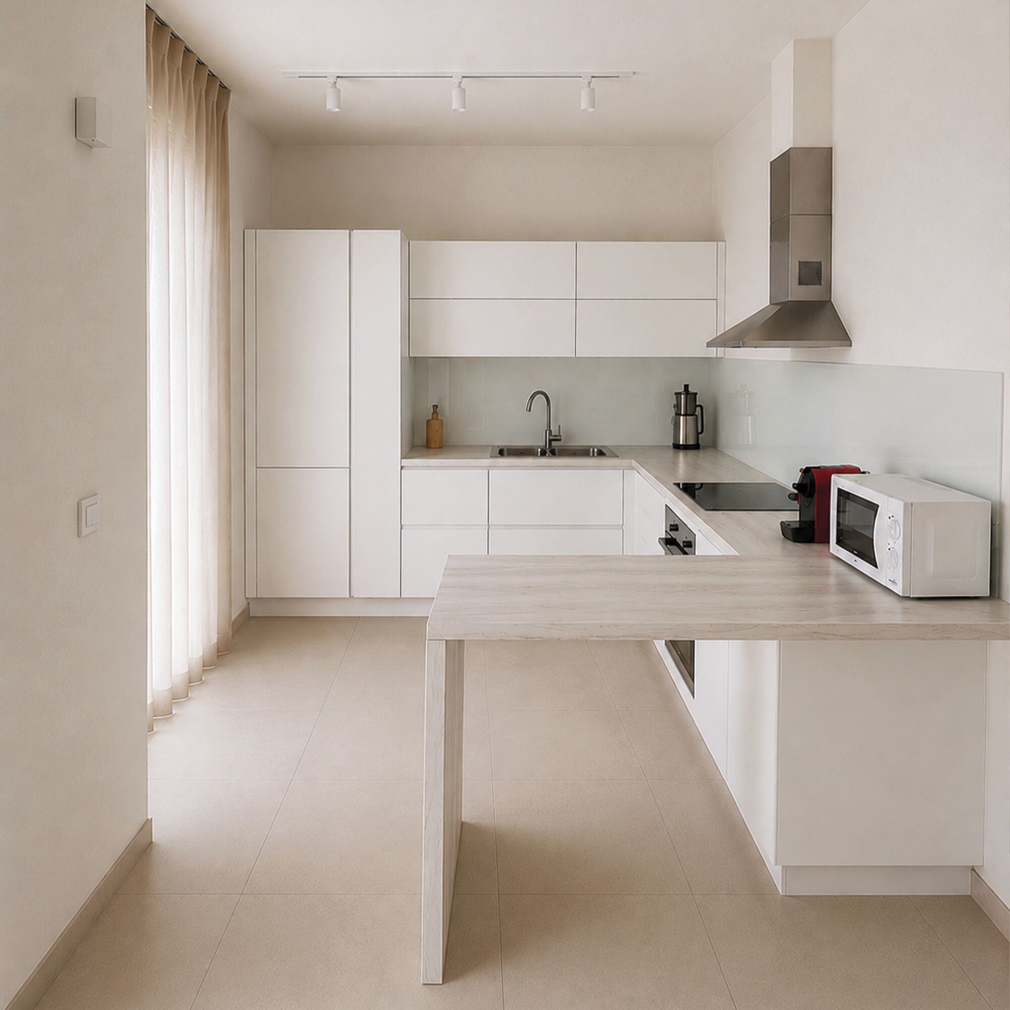 Une cuisine moderne avec des meubles blancs, un évier en acier inoxydable, un four à micro-ondes et un four encastré.