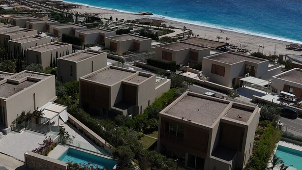 A coastal residential area with modern buildings, a beach, and a swimming pool.