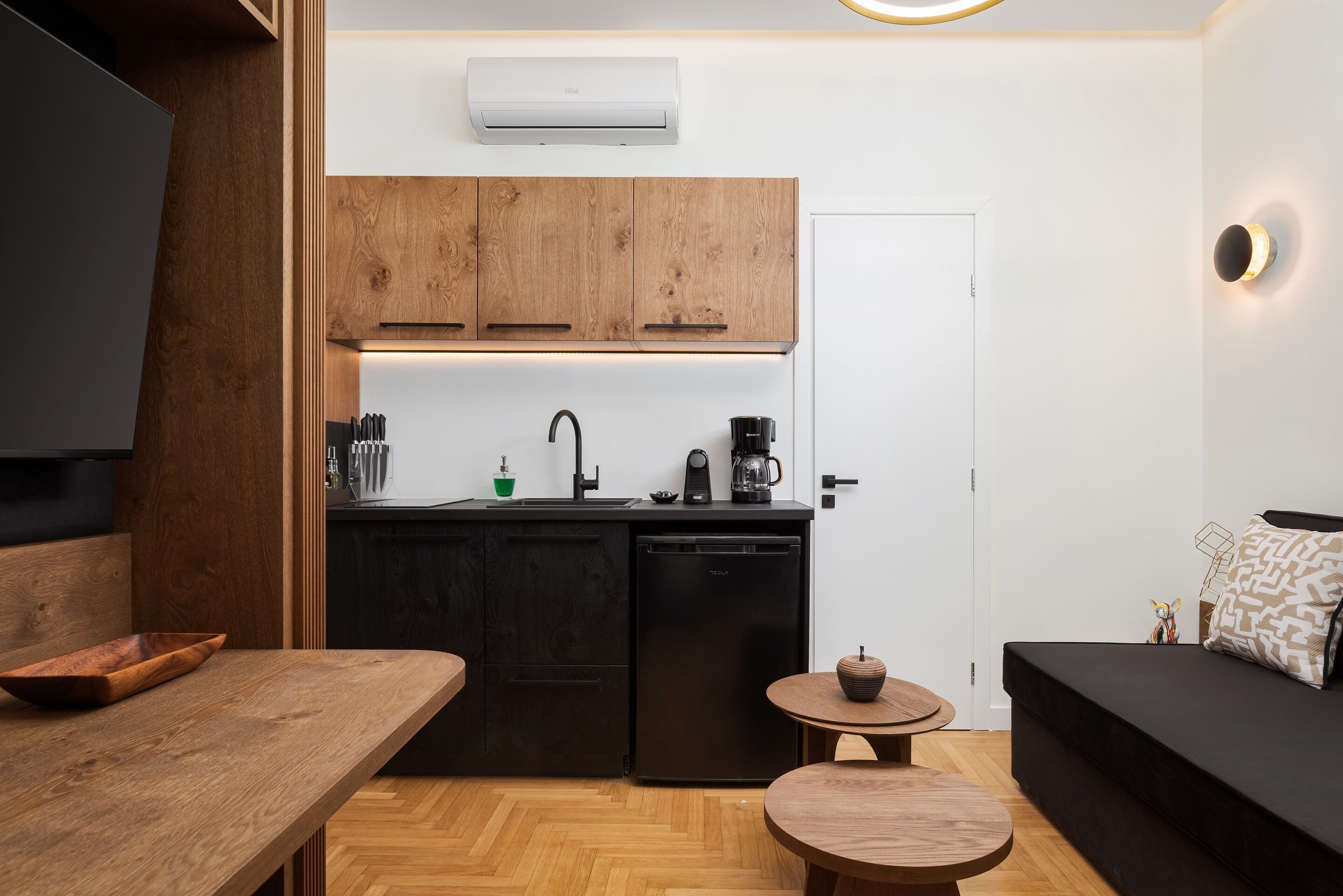 A compact kitchen with wooden cabinets, a black dishwasher, and a coffee maker.