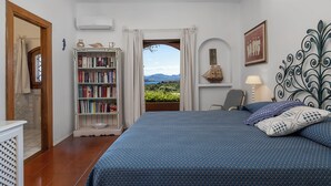 A bedroom with a bed, a bookshelf, a desk, and a view of the outdoors. - Classic villa, Cala di Volpe, minutes away from Sardinia's most iconic beaches (Sardegna)