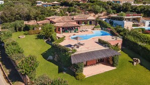 A large house with a swimming pool, surrounded by lush greenery and a hilly landscape. - Classic villa, Cala di Volpe, minutes away from Sardinia's most iconic beaches (Sardegna)