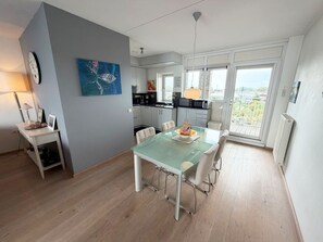 Eine moderne Küche mit Essbereich, einer Uhr an der Wand und Blick durch die Glastür.