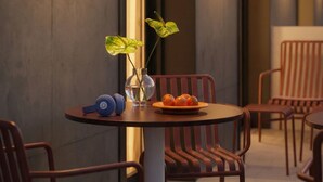 Un comedor moderno con una mesa redonda, sillas, un florero con flores, un plato de fruta y auriculares sobre la mesa.