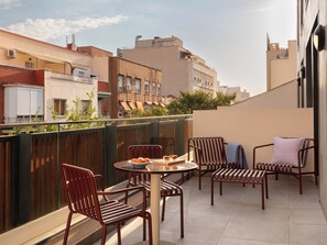 Un balcón con mesa, sillas y vistas de la ciudad.
