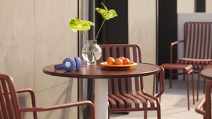 Una mesa redonda con un jarrón de flores, un plato de fruta y un par de audífonos.