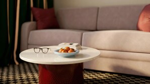Una mesa redonda con un frutero y vasos, un sofá y un suelo a cuadros.