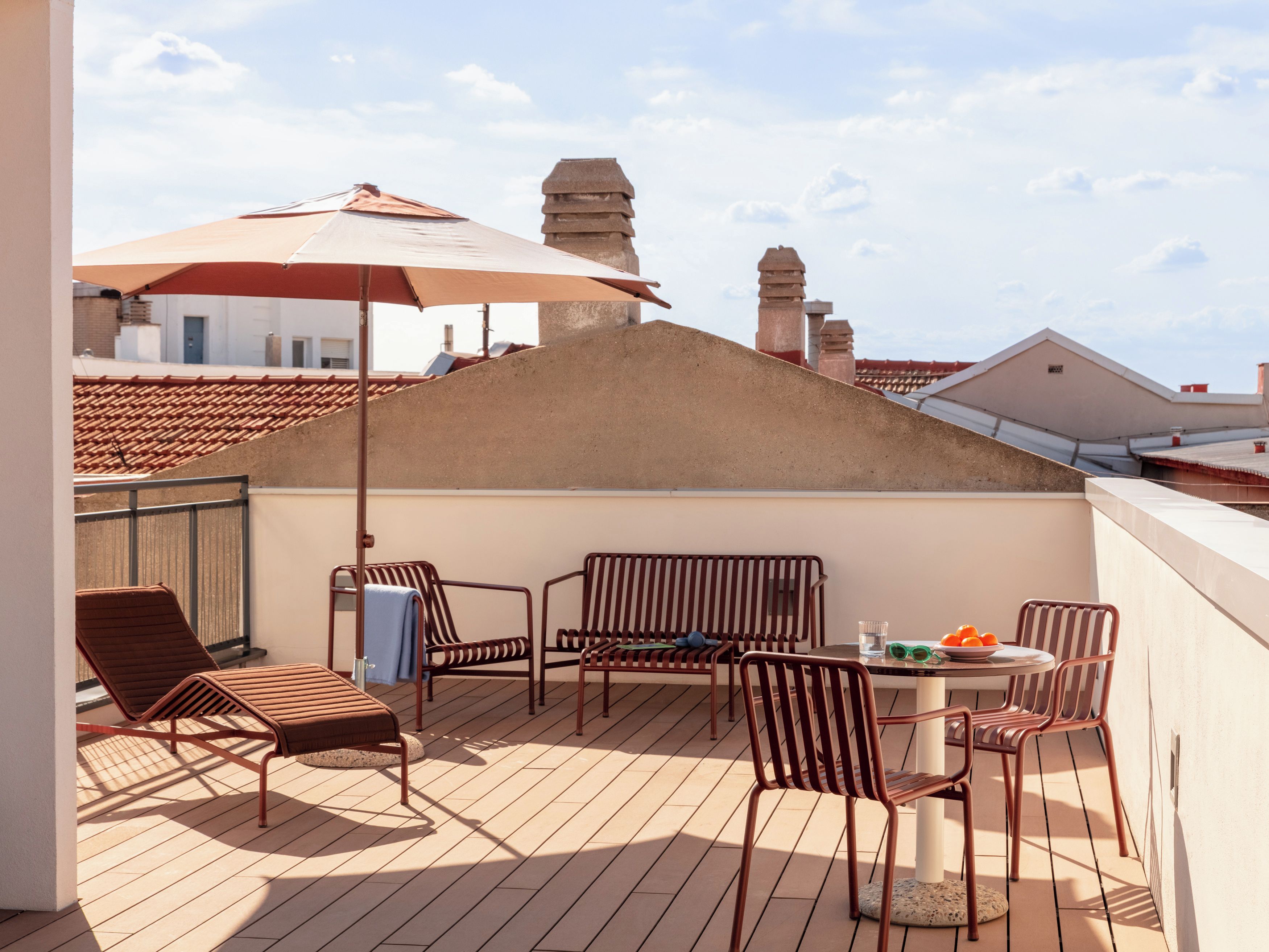 A rooftop terrace with a table, chairs, and a large umbrella.