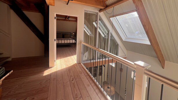 Ein Holzinnenraum mit Schlafzimmer im oberen Bereich, einer Treppe und einem Oberlicht.