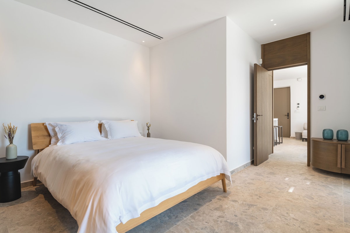 Um quarto moderno com uma cama grande, uma mesa de cabeceira e uma cabeceira de madeira.