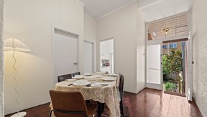 Comedor con una mesa preparada para cuatro, una lámpara y vistas al jardín trasero.