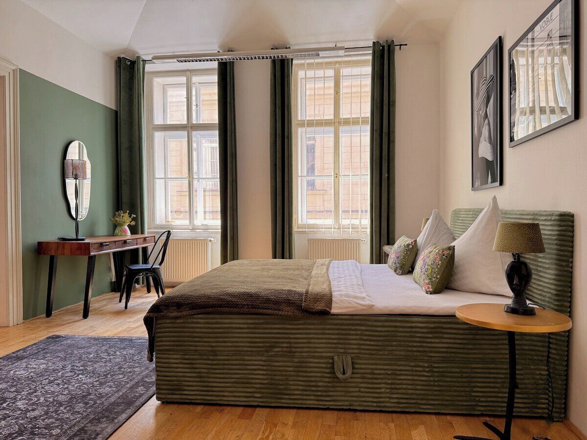 A bedroom with a bed, a desk, a chair, a lamp, and a window.