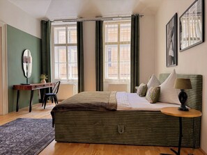 Ein Schlafzimmer mit Bett, Schreibtisch, Stuhl, Lampe und Fenster.