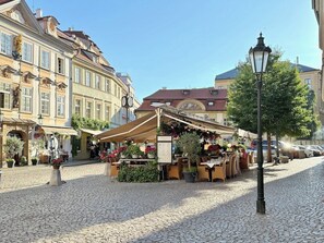 A cobblestone street with a café, outdoor seating, and historic buildings. - Style & Design Apartment im Herzen von Prag für 8 Personen (Prag)