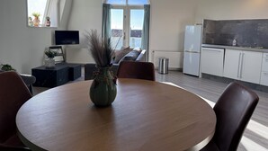 Een moderne woonkamer met een ronde houten tafel, een bank en een televisie aan de muur.