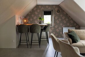 Een gezellig slaapkamer op zolder met een schuine plafond, een klein zithoekje met twee stoelen, een bank en een raam met uitzicht.
