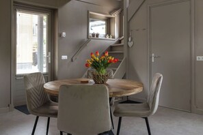 Een eetruimte met een ronde houten tafel, vier beklede stoelen en een vaas tulpen.
