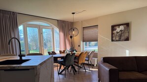 A modern kitchen with a marble countertop and a dining area with wooden chairs and a glass-top table. - Holiday home Residenz Polderblick 3 in Burgerbrug. Suitable for 4 people, 2 bedrooms. (Burgerbrug)