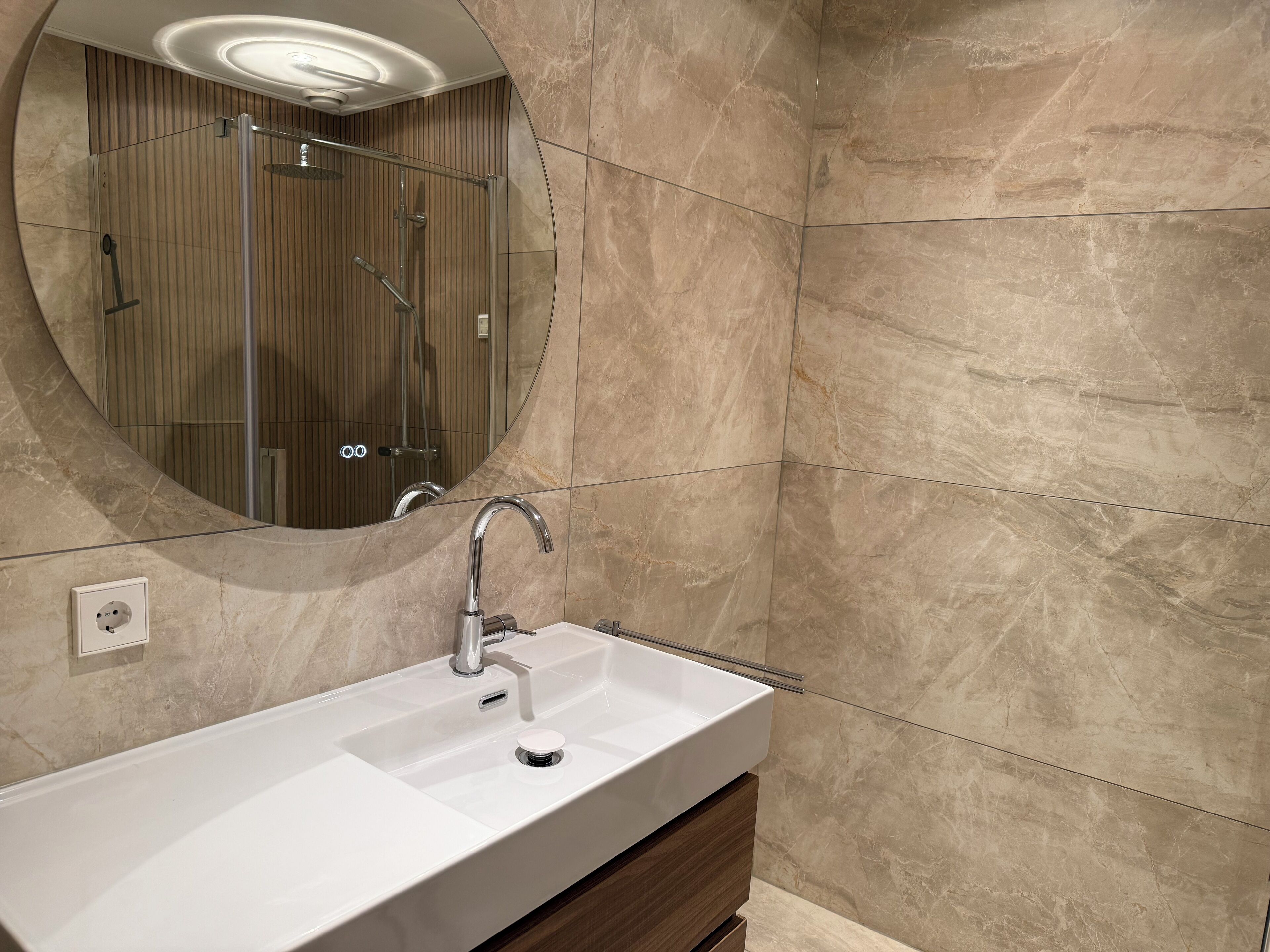 Une salle de bain moderne avec un lavabo rectangulaire, un miroir et un espace douche.
