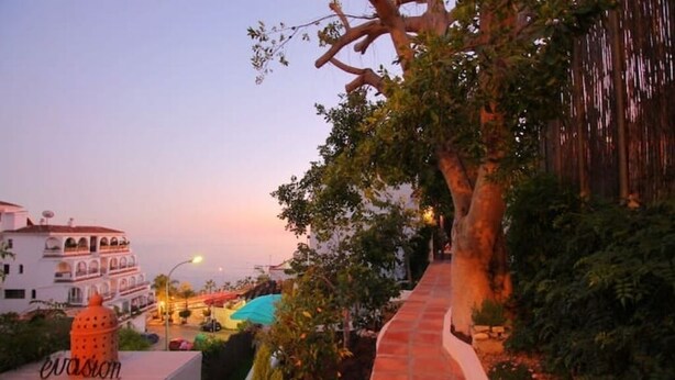 A sunset view overlooking a building with a tiled pathway and a tree. - CASA EVASION at the foot of the beach, incredible views surrounded by a beautiful garden. (Almuñécar)