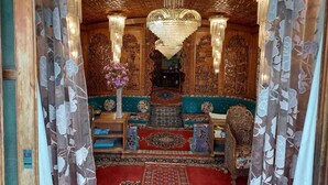 A room with ornate wooden carvings, a chandelier, and a floral arrangement. - DeLaila Luxury Houseboat by Shahnawaz  (Srinagar)