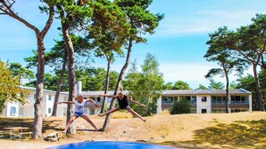 Un terrain de jeux avec un toboggan et des arbres, et un bâtiment en arrière-plan.