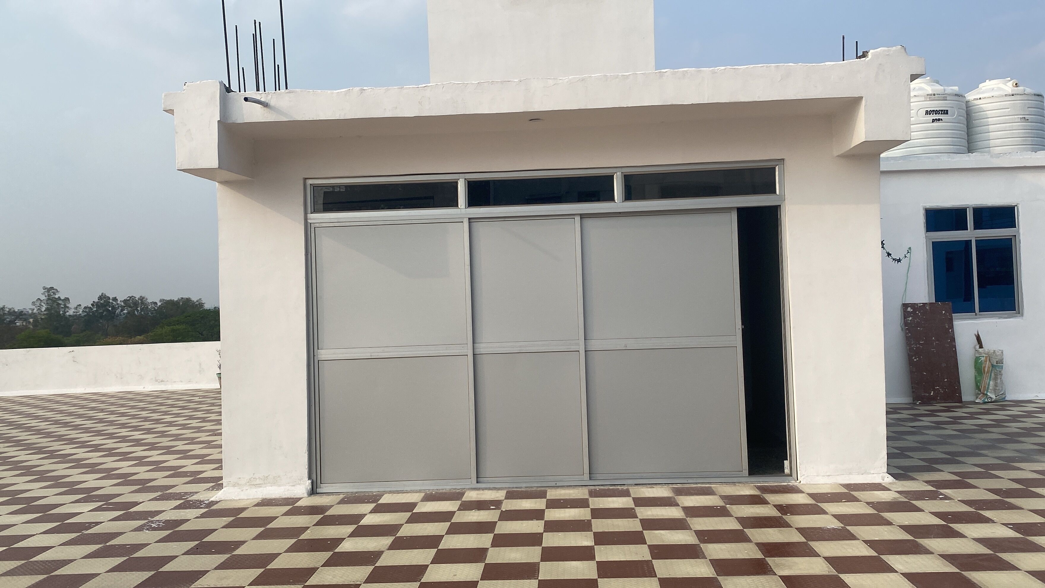 A building with a large, closed metal door, a checkered floor, and a white exterior wall.