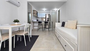 Ett modernt och kompakt bostadsutrymme med ett litet kök, matplats och en soffa.