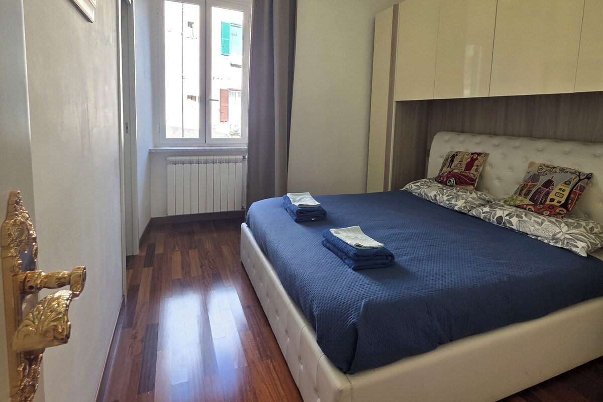 A bedroom with a bed, a window, a radiator, and a door with a golden handle.