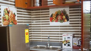 Cucina con mobili in legno, frigorifero in acciaio inossidabile, lavello e schienale piastrellato.