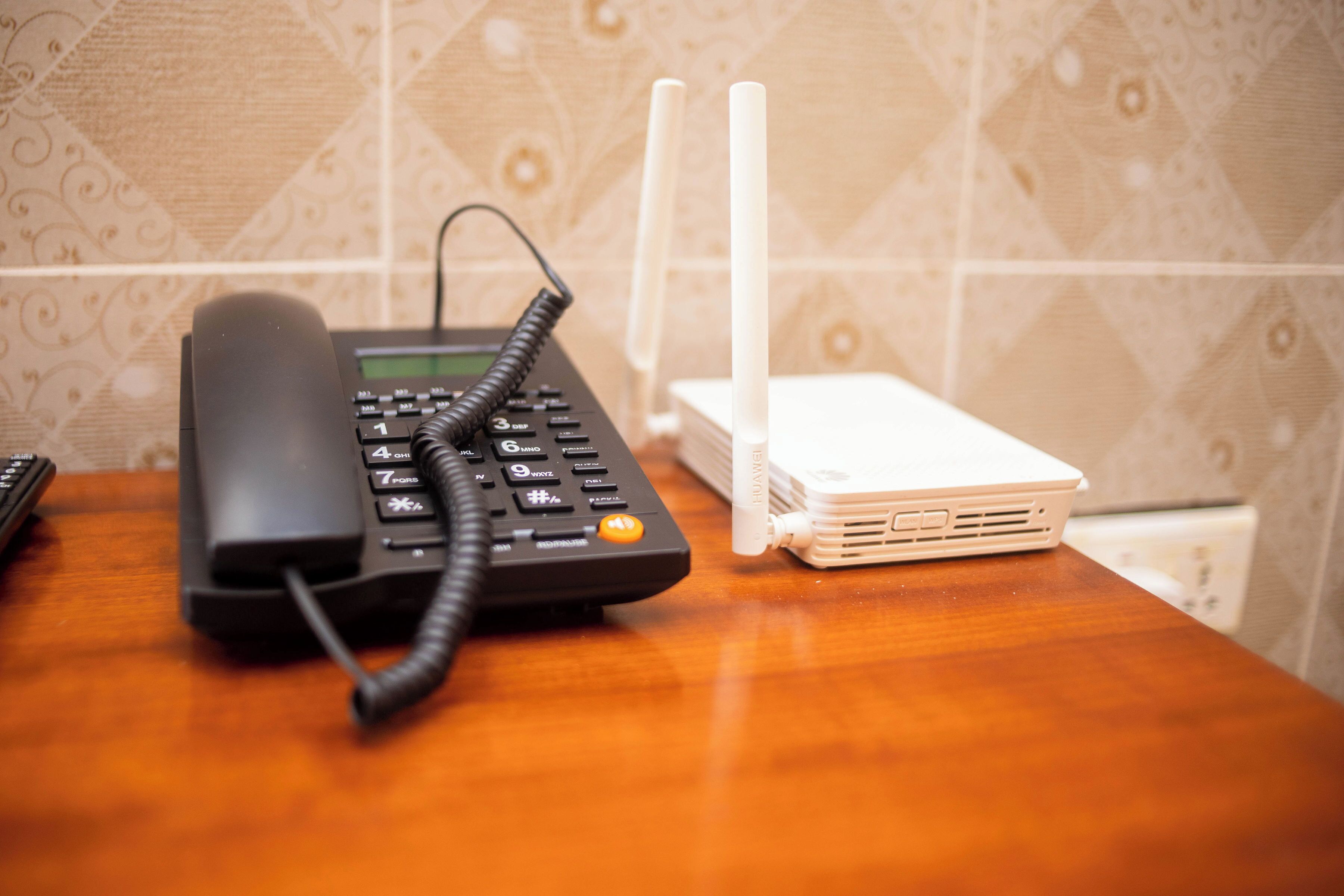 Um telefone e um roteador branco sobre uma mesa de madeira.