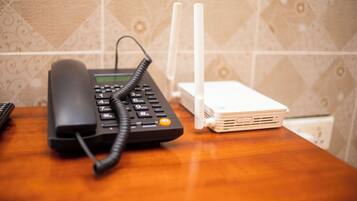 Um telefone e um roteador branco sobre uma mesa de madeira.