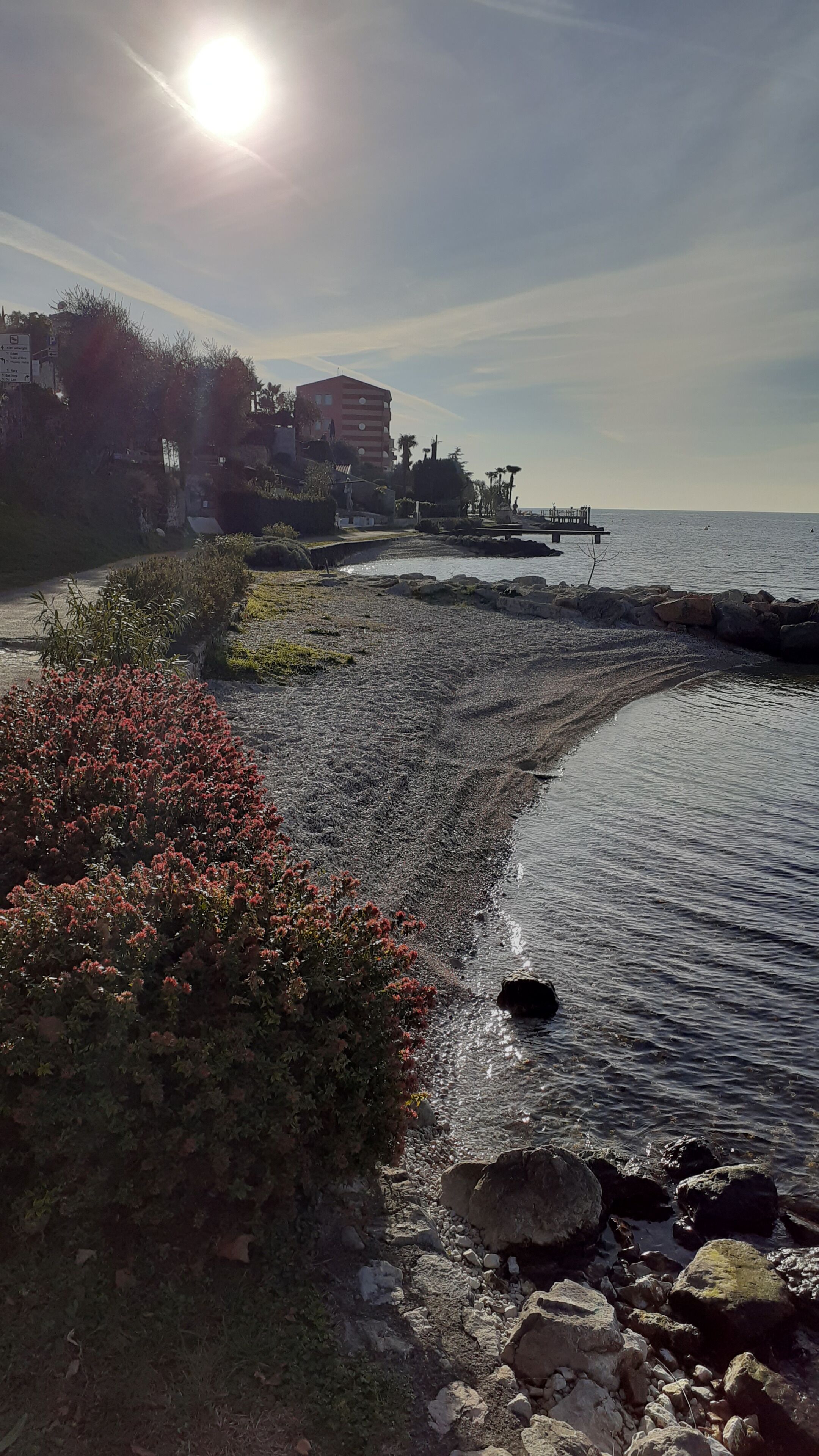 A coastal area with a rocky shoreline, a bridge, and buildings in the background.