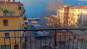 Een balkon met uitzicht op een jachthaven, boten en bergen op de achtergrond.