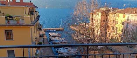 Un balcón con vista a un puerto deportivo, barcos y montañas al fondo.