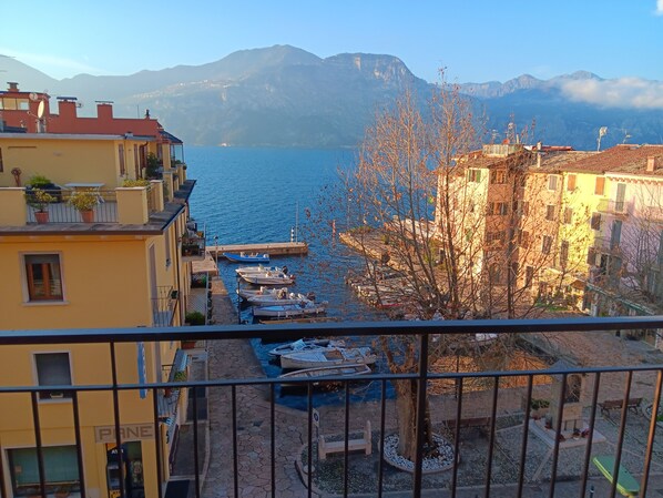 A balcony with a view of a marina, boats, and mountains in the background. - Appartamenti Casa Adua (Porto)