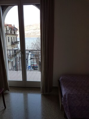 A room with a large sliding glass door leading to a balcony overlooking a body of water and a building with balconies. - Appartamenti Casa Adua (Porto)