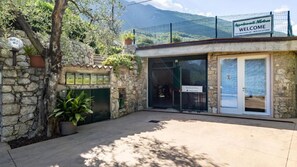 A stone building with a sign reading "Welcome" and a mountain view in the background. - Appartamenti Casa Adua (Porto)
