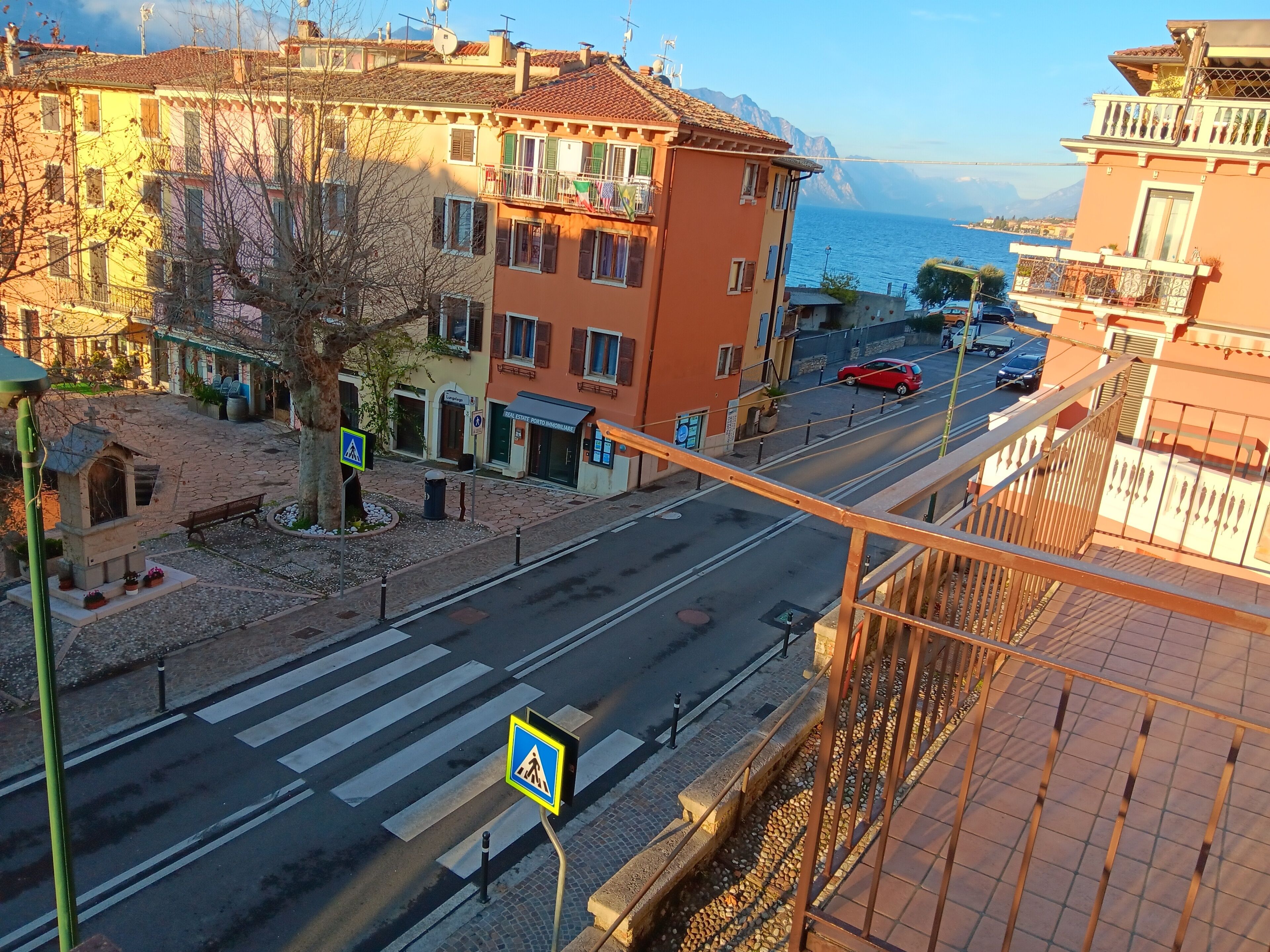 Straßenansicht mit Gebäuden, einer Fußgängerampel und Blick auf das Meer.