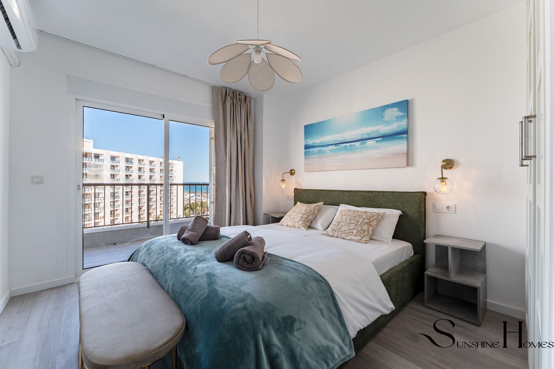 A modern bedroom with a large bed, a view of the sea, and a balcony.