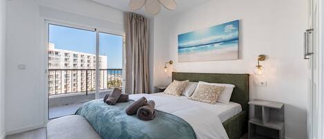 Un dormitorio moderno con una cama grande, vista al mar y un balcón.