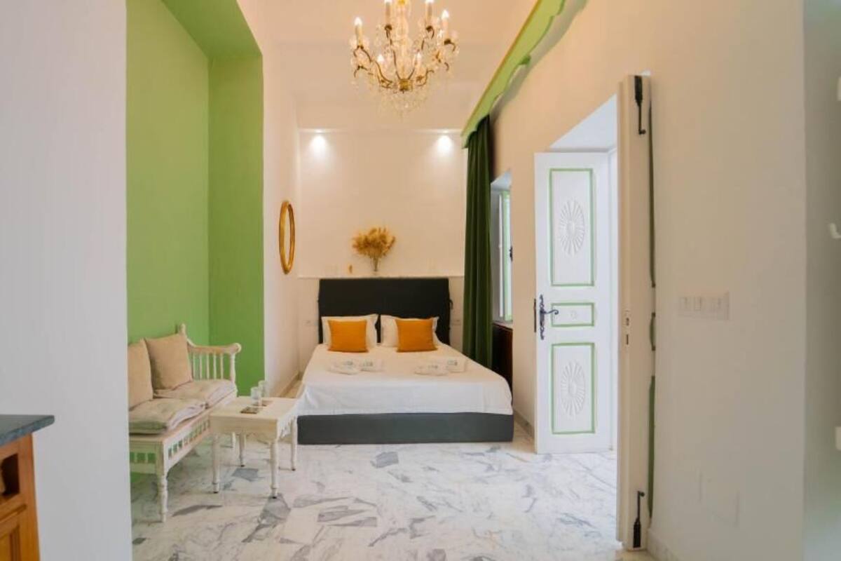 Una camera da letto con un letto, un comodino, una sedia e un lampadario.