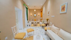 A hallway with a white sofa, yellow chairs, a round table, and a mirror on the wall. - Dar Majoul (Tunis)