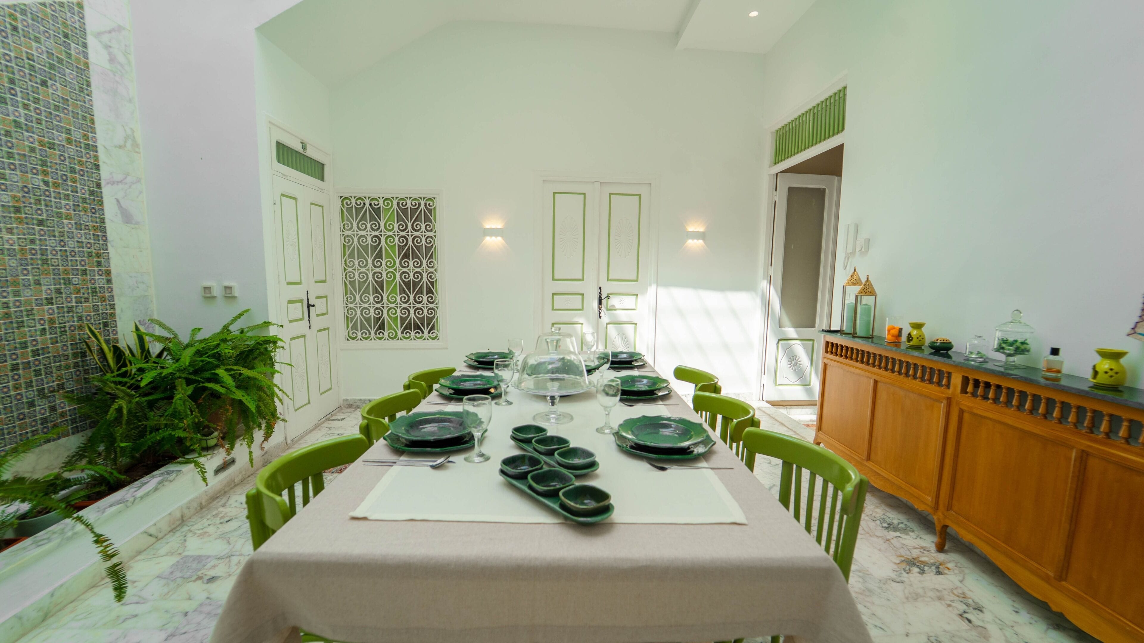 Un comedor con una mesa larga dispuesta para una comida, rodeada de sillas.