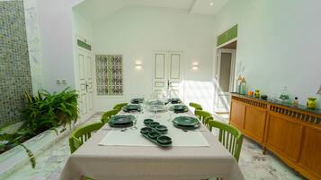 Un comedor con una mesa larga dispuesta para una comida, rodeada de sillas.