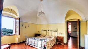 Un dormitorio con una cama, una mesita de noche, una lámpara y vistas al exterior.