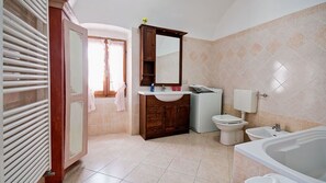 Un baño con bañera, inodoro, lavabo y un espejo grande.