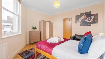 A bedroom with a bed, a wardrobe, a radiator, a window, and a door.