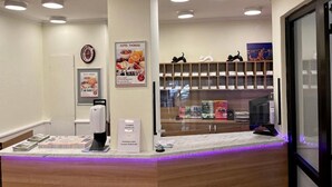 A hotel reception area with a marble counter, a clock, and a poster advertising hotel amenities. - Thomas Hotel Budapest (Budapest)