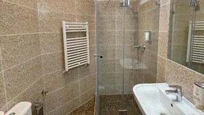 A modern bathroom with a glass-enclosed shower, a white sink, and a toilet. - Thomas Hotel Budapest (Budapest)